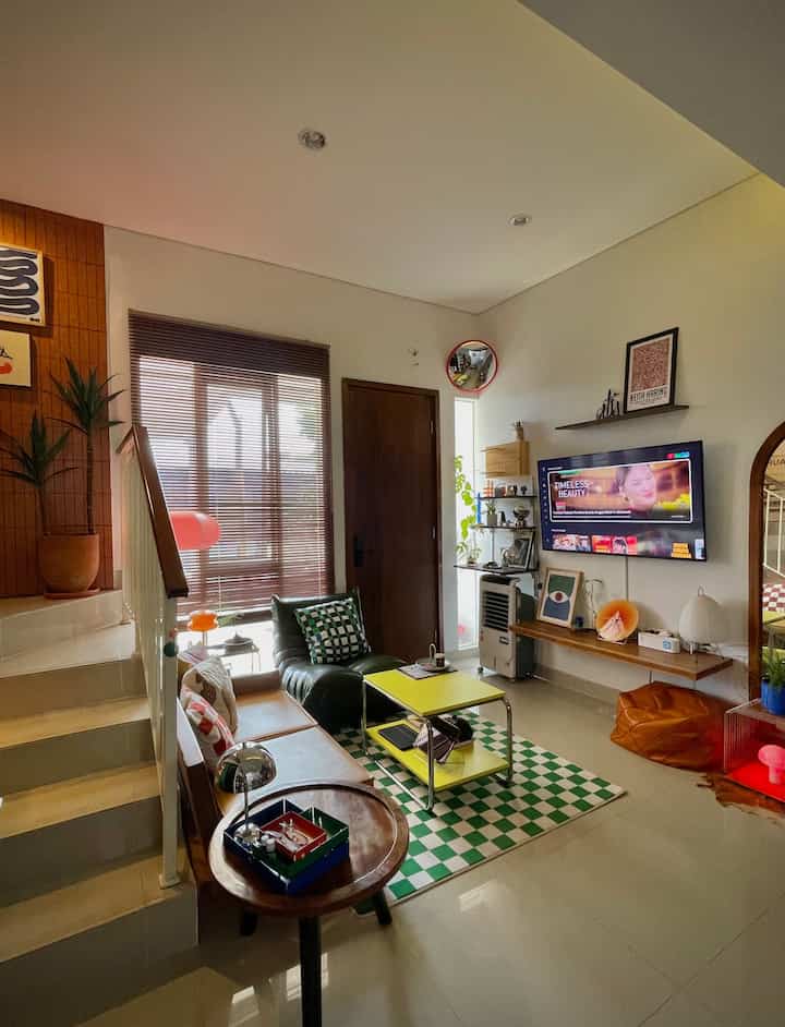 Mendekorasi Living Room dengan Pop Up Color 🛋️
.
Living Room adalah ruang yg paling merepresentasikan kepribadian penghuninya, jadi tempat kami untuk mengekspresikan diri mengeksplor warna & tekstur!
🪵Furnitur Kayu. untuk mengkombinasikan banyak warna pada ruangan, butuh material netral favorit yaitu kayu. Kami aplikasikan pada wooden blind, kursi sofa 2 seater, coffee table, ambalan Tv floating kayu jati & rak floating motif kayu. 
💼Busa Sofa berbahan kulit (sintetis). Saya suka tekstur kulit terutama pada busa sofa kami pilih warna kuning mustard yg looksnya calming tp tetap oustanding, lalu warna hijau army pada togo sofa dan bean stool.
🌊 Karpet Motif kotak. Dengan warna hijau putih yg pop up color, ternyata cocok dikombinasikan dengan coffee table stainless, top table warna kuning dari Ikea yg keduanya bisa menciptakan mood ala-ala cafe. 
💡 Indirect Lighting. Makin banyak lampu, makin estetik. Lampu-lampu meja berbahan chrome, kaca, rice paper, Led strip pada Tv dan lampu lantai gift dr Ohouse mampu menciptakan ambience ruangan yg berbeda beda, apalagi dikombinasikan dgn smartlamp full color yg bisa diganti2 mood warnanya!
🗿Dekorasi meja, dinding & sofa. Seperti Poster, Vas bunga, tempat lilin, diffuser, cushion cover bermotif. Kalau masih takut dgn warna yg terlalu masif, bisa mulai dulu dari item-item dekoratif kecil ini agar menciptakan mood warna pada ruangan.
🌿Tanaman. Menciptakan elemen natural pada ruangan bisa menciptakan estetika, baik tanaman asli pada meja & rak floating, maupun pohon artificial yg bisa mengelevasi ruangan.
.
Gimana teman-teman udah Cozy belum living room ini buat area berkumpul? 🤗
#StylingRuangTamu #DekorasiLivingRoom #InspirasiLivingRoom #WoodenBlind #Ambalanfloating #FloatingShelves #BeanStoolKulit #lightingroom #SmartLamp #PopUpColor
