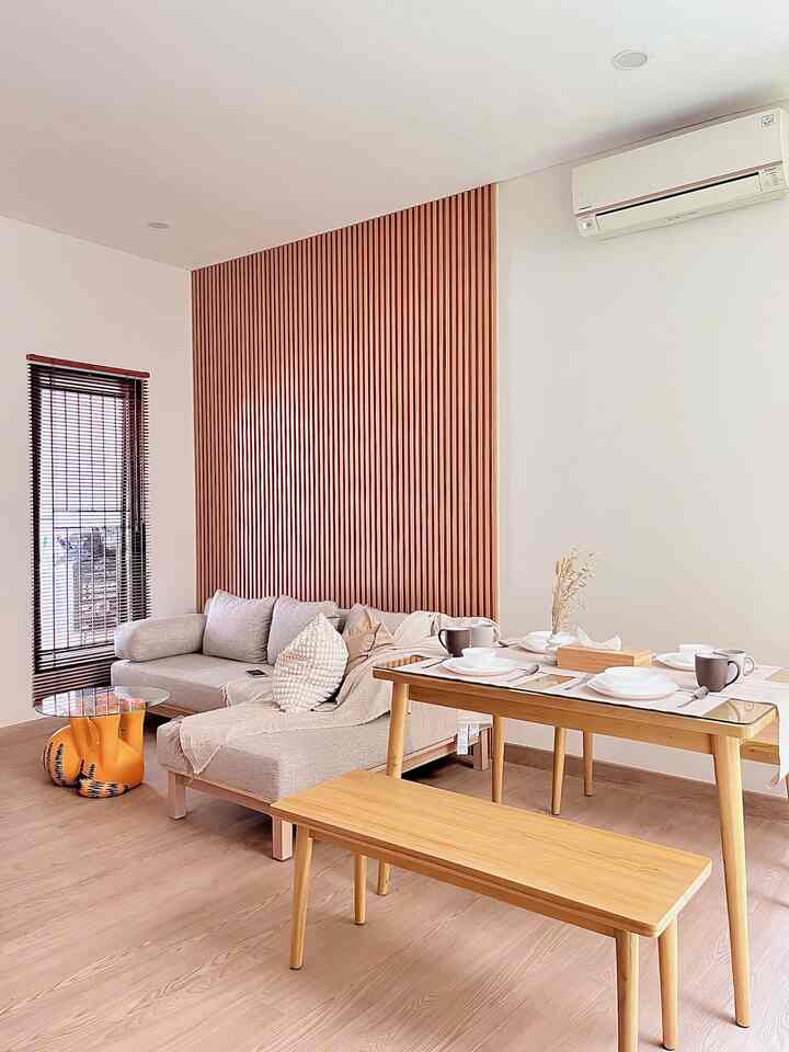 Natural-tone living room for four, featuring wood panel wall, compact sofa and dining table in a clean space