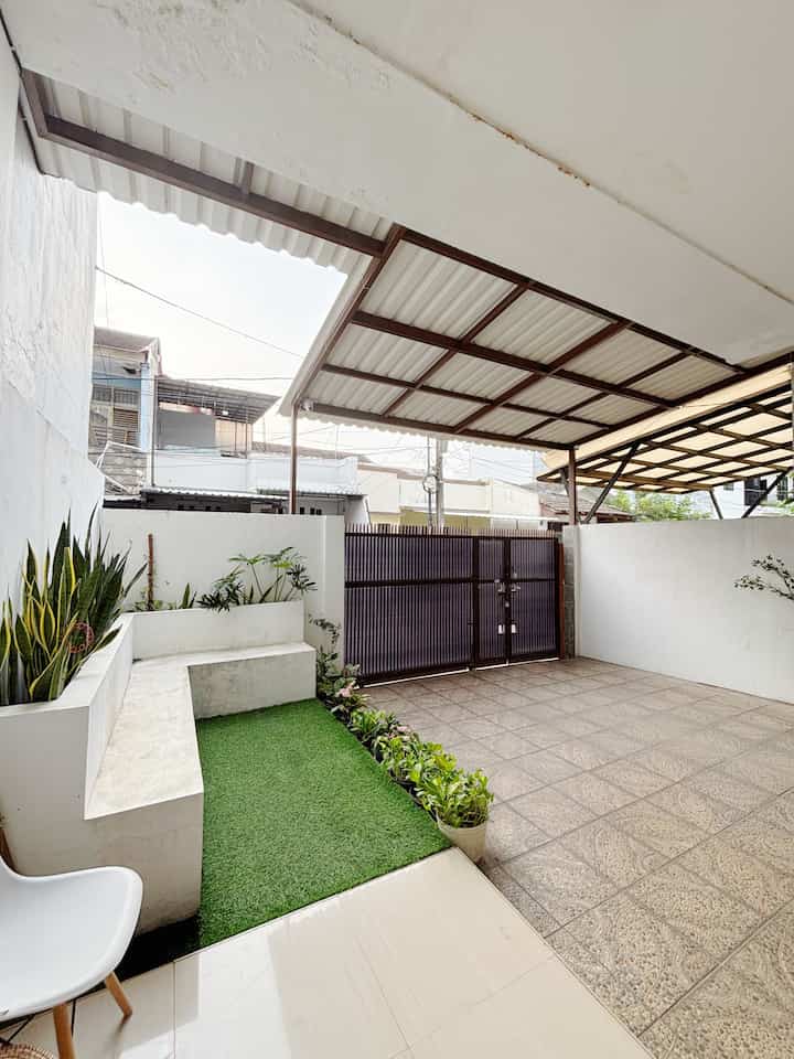 Spacious carport and terrace area featuring white and khaki tones with artificial grass, clean and practical outdoor relaxation space