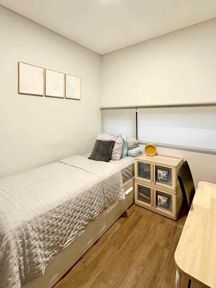 Natural color wood-tone compact bedroom featuring a single bed with storage and custom storage units in a tidy space