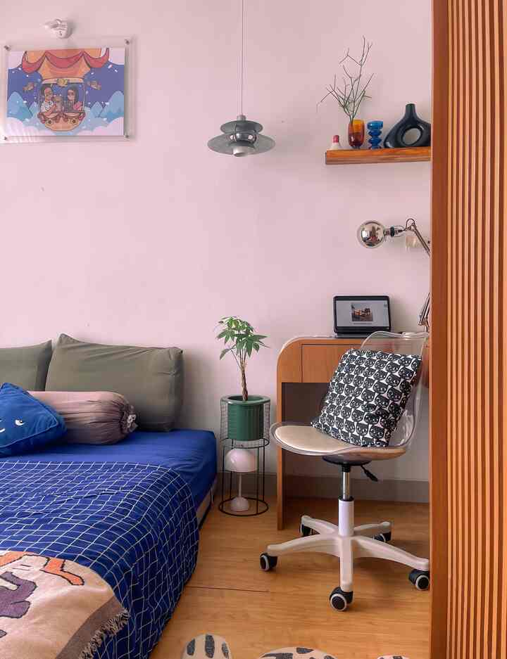 Modern single household bedroom with blue bedding and wood tone furniture featuring a home office setup