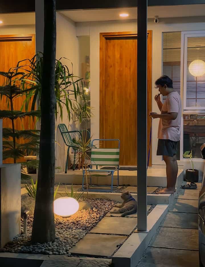 Natural color and wood tone outdoor entrance featuring a cat and warm outdoor lighting in a cozy nighttime setting