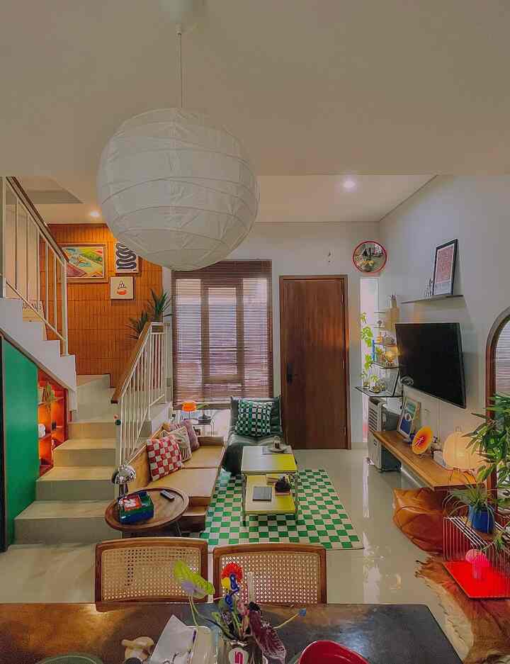 Natural-toned living room featuring a white pendant light, wooden furniture, green cushions and checkerboard rug with cozy atmosphere