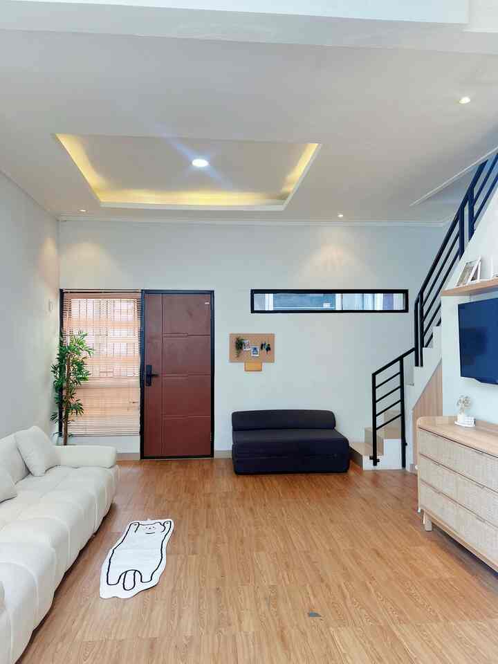 Bright white and wood tone compact living room featuring sofa bed and TV stand with a clean, simple atmosphere