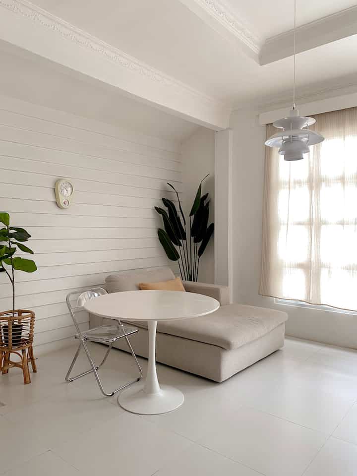 White and beige toned living room featuring beige sofa and round white table in a modern natural style
