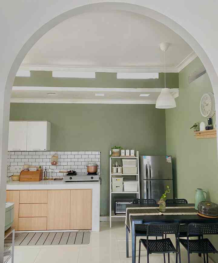 Kitchen and dining room with pale green walls and white arched doorway, black dining table and chairs, creating a modern natural ambiance