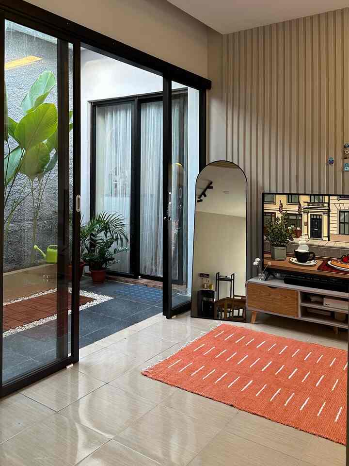 A bright white and beige living room featuring an orange carpet and wood-toned TV stand with a cozy, spacious atmosphere