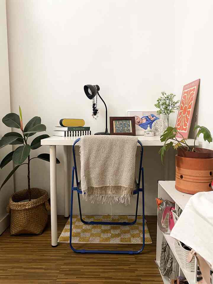 White and blue toned compact home office featuring a white desk and blue folding chair, with a calm and natural atmosphere