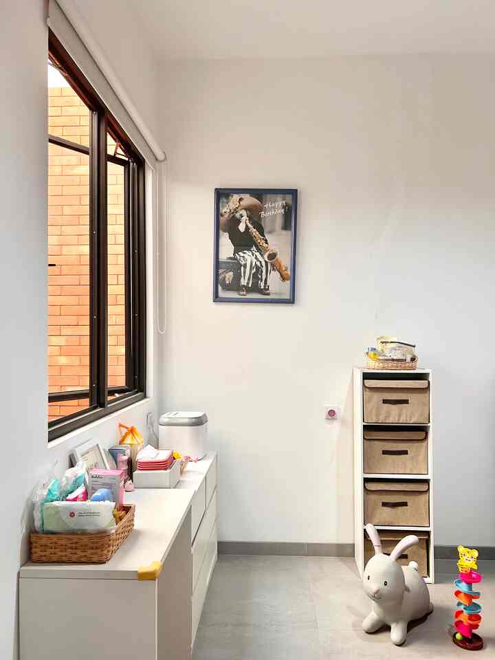 Bright white kids' room featuring white drawer cabinet with toys and organized storage, creating a cozy neat space