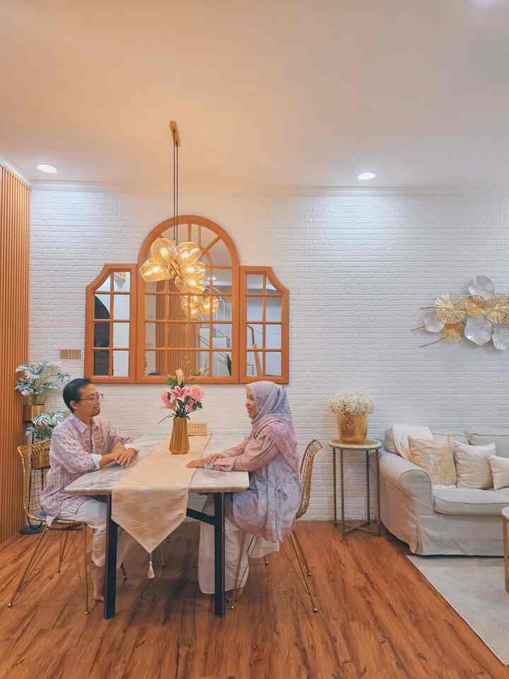 Warm wood tone flooring and white walls in a living dining room, featuring gold accents and cozy pendant lighting in a family space
