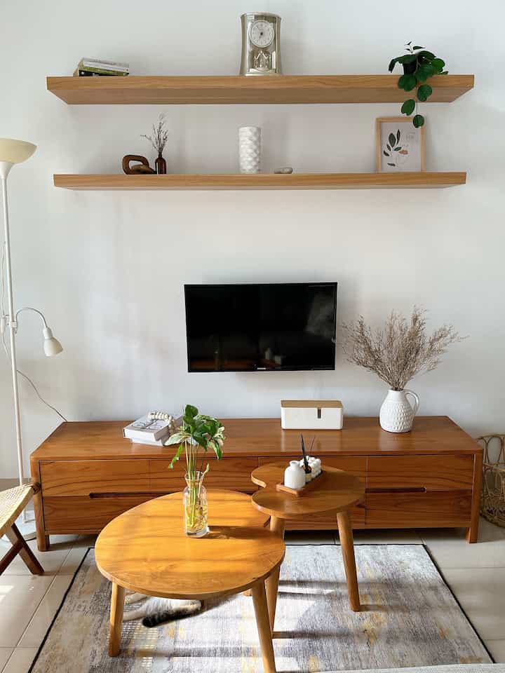 Natural wood tone and white living room featuring wall-mounted TV and round coffee tables with a simple interior design