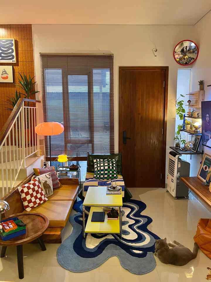 Wood tone living room with blue and yellow accents, featuring sofa, rug, and various lighting creating a cozy atmosphere