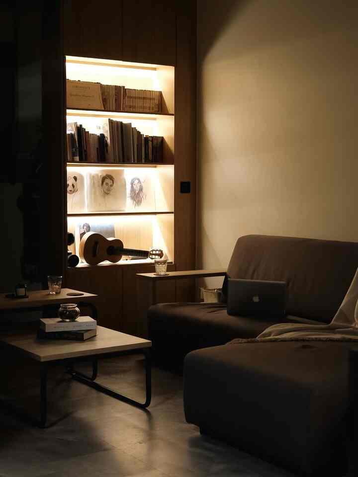 Warm natural-toned living room featuring illuminated bookshelf and spacious sofa with a simple, calm atmosphere