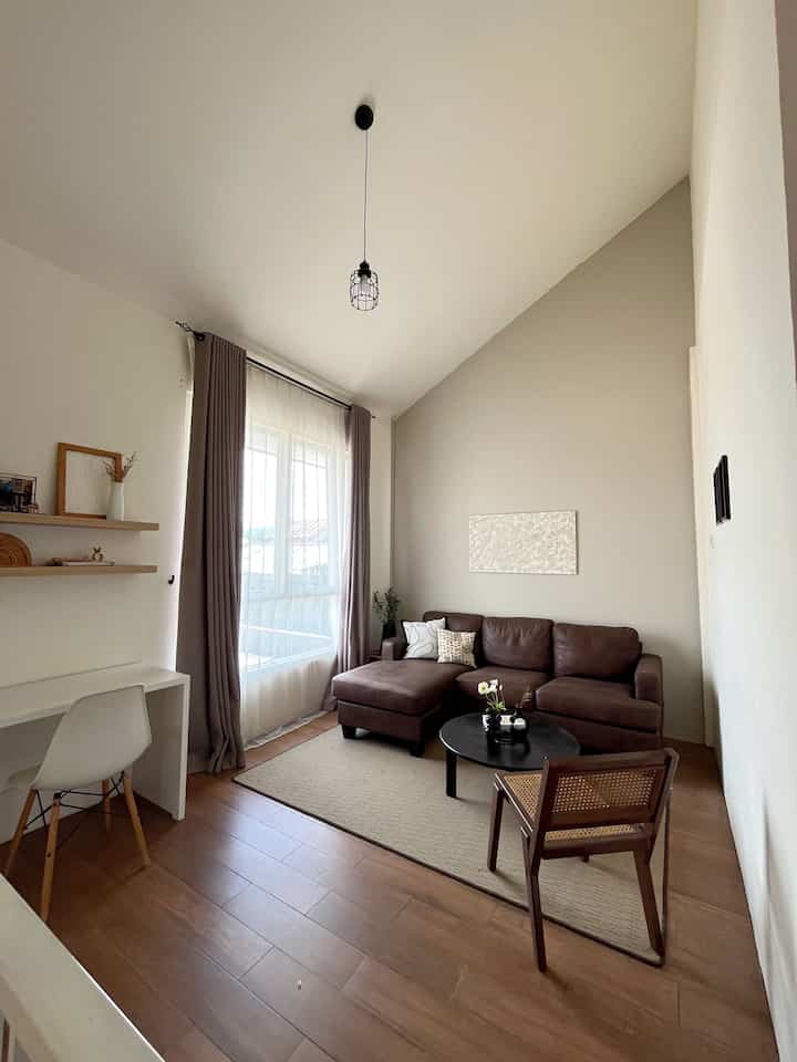 Beige and brown toned living room featuring Louise sectional sofa and rattan chair, creating an open and cozy atmosphere