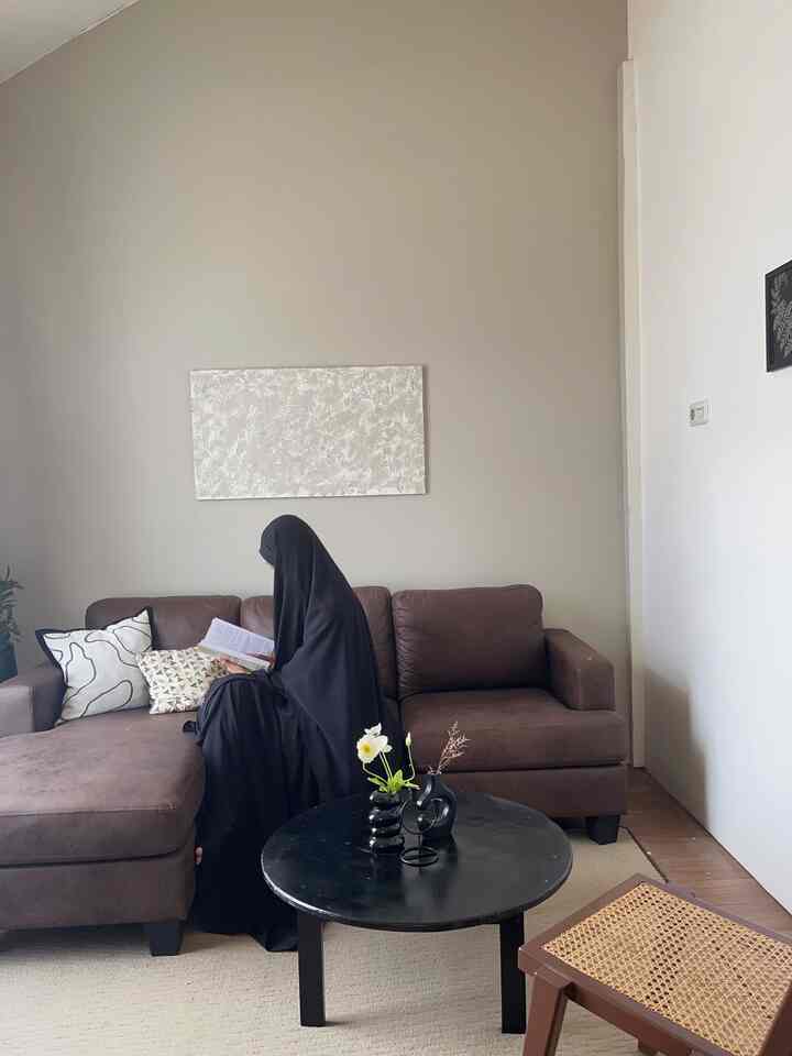 Beige and brown toned living room featuring sectional sofa and black round coffee table in a simple modern style space