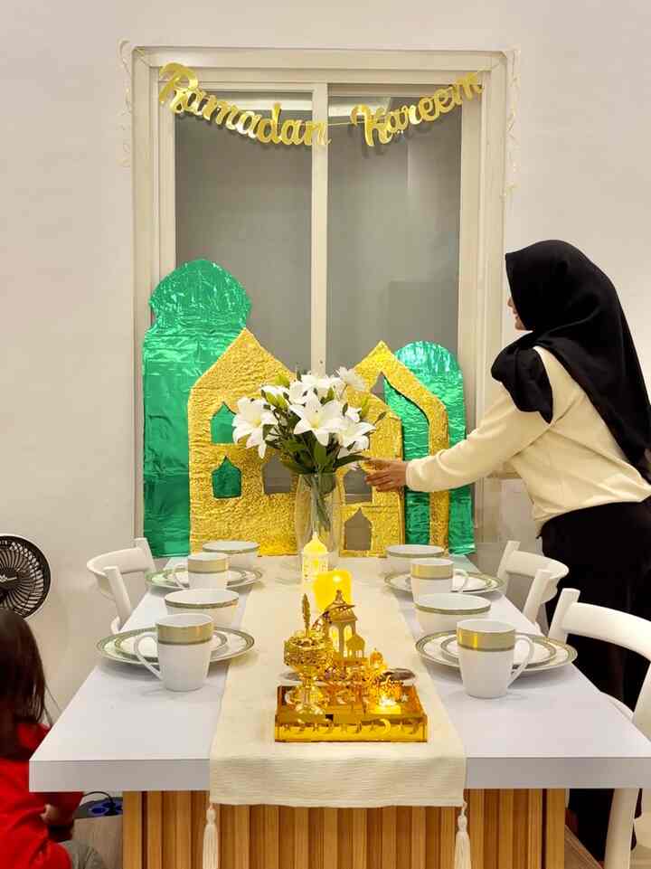 White and gold toned dining room featuring a vase with lilies and elegant event decorations creating a festive atmosphere