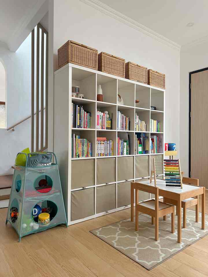Natural tone kids' room with children's desk and chairs, large organized bookshelf for storage