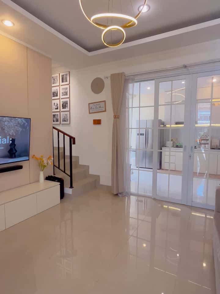 Bright white and beige living room featuring a minimal sofa and glass door connecting to the kitchen with a clean interior
