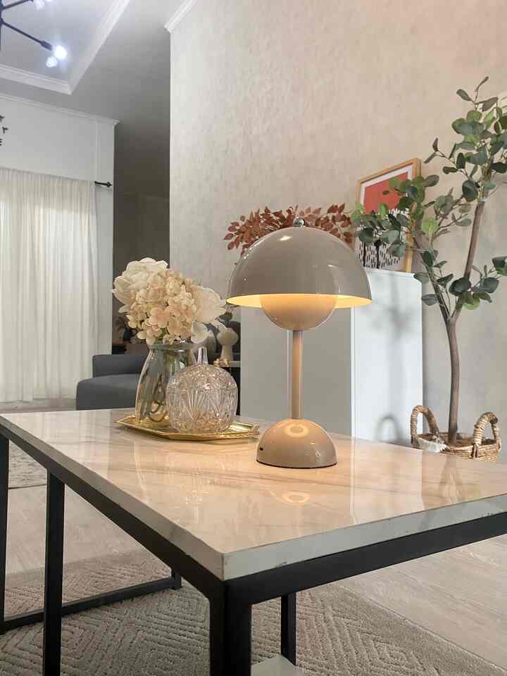Bright modern living room featuring a white mushroom table lamp, flower vase, and gold tray on a marble coffee table with black metal legs