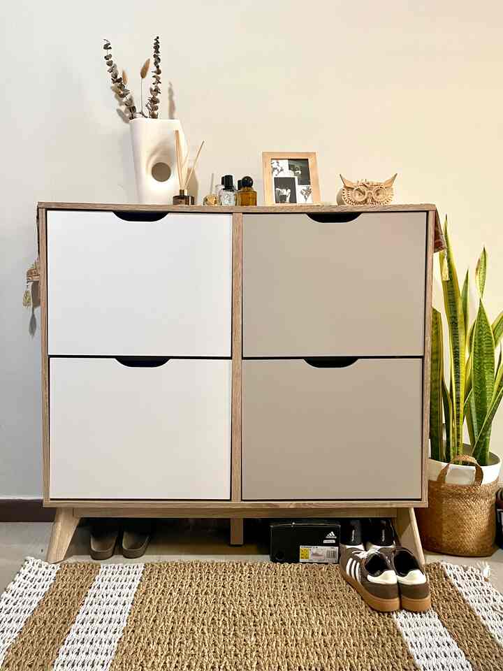 Natural wood tone shoe cabinet with white and beige panels in a neat entrance space