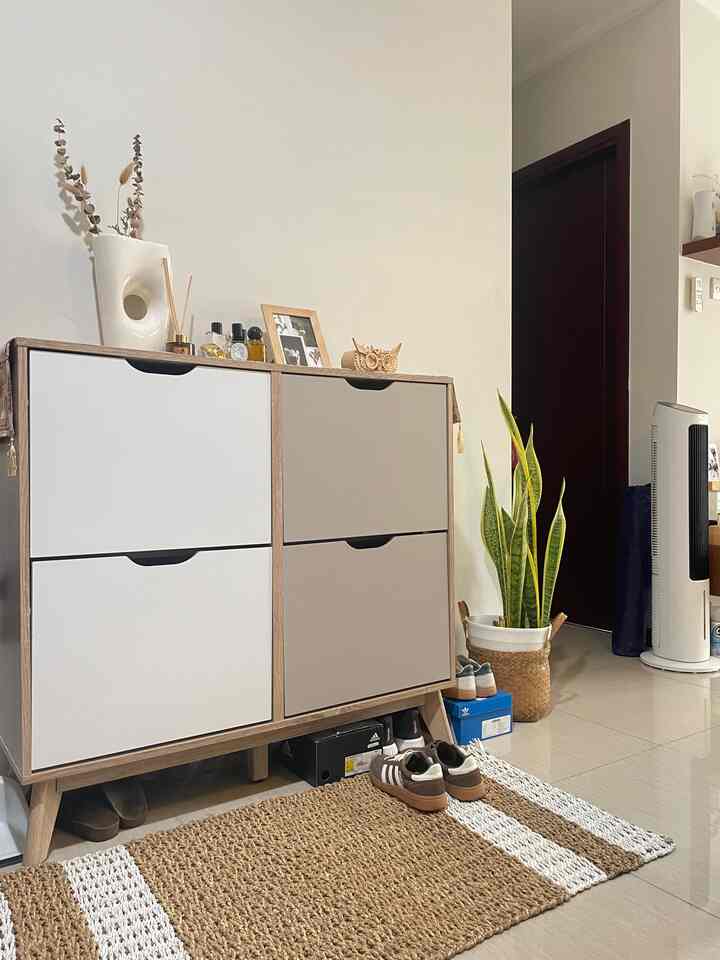 Natural style entrance with beige and white tones featuring a storage cabinet, floor mat, and shoes arranged neatly