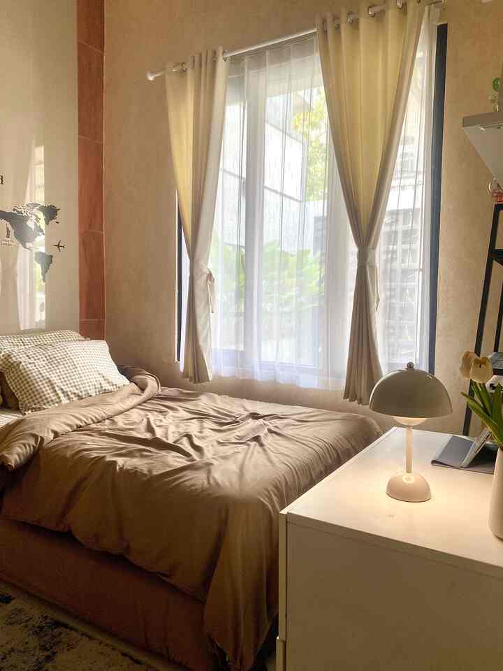 Beige and brown toned bedroom featuring a large bed, white nightstand and table lamp creating a cozy atmosphere