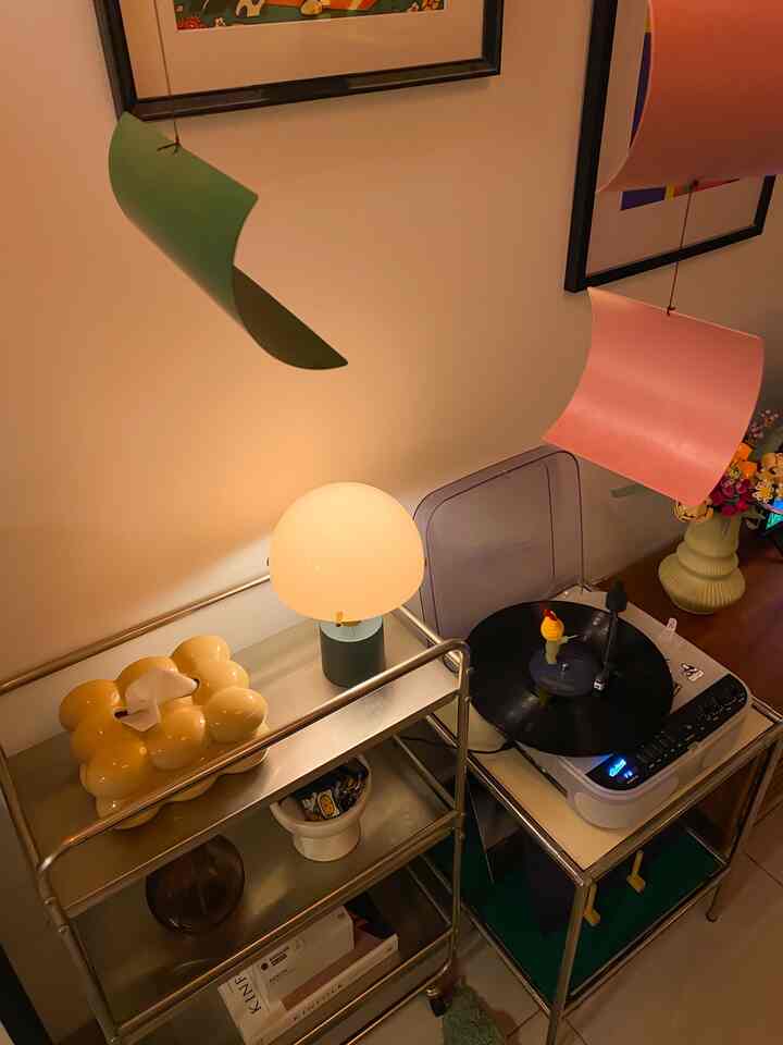 Cozy home cafe corner featuring warm lighting table lamp and vinyl record player on metal storage carts