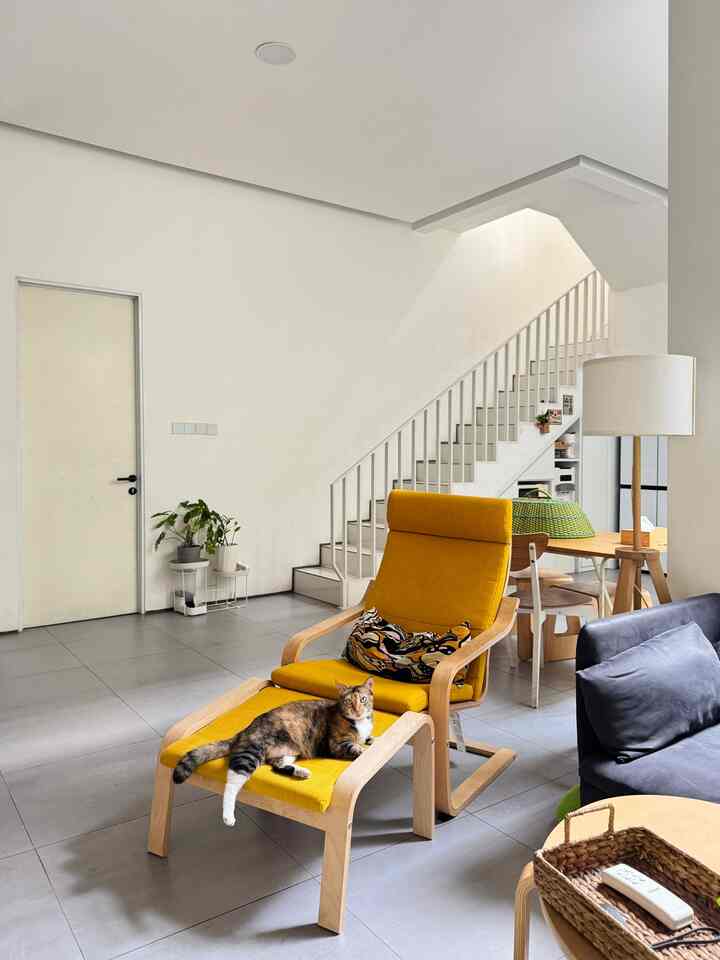Living room with white walls and natural wood tones, featuring a yellow armchair with a cat resting comfortably, creating a cozy atmosphere