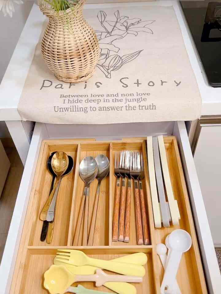 Wood tone kitchen drawer featuring a neatly organized cutlery tray with spoons, forks, and knives arranged tidily