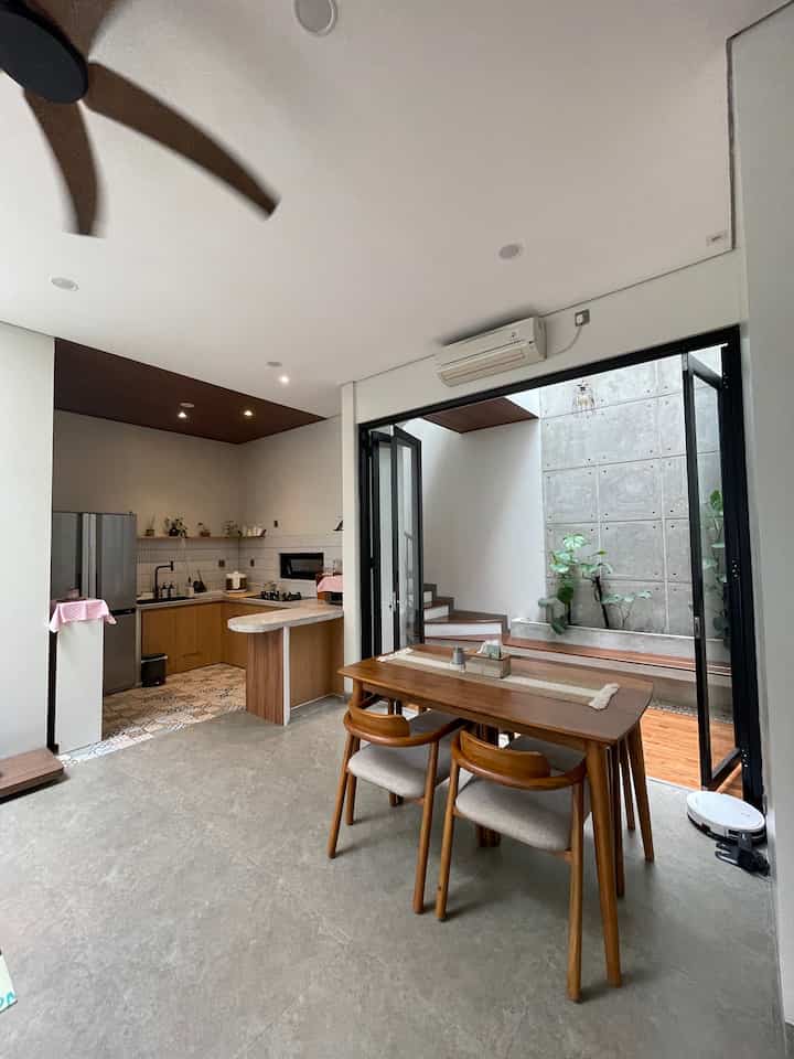 Bright white and brown toned dining room and kitchen featuring natural modern wooden furniture with an airy atmosphere