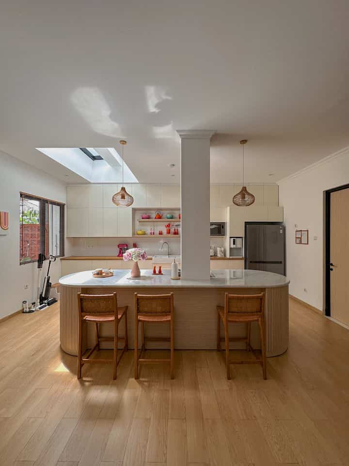 A white and wood tone kitchen featuring a kitchen island and pendant lights with a natural, simple atmosphere