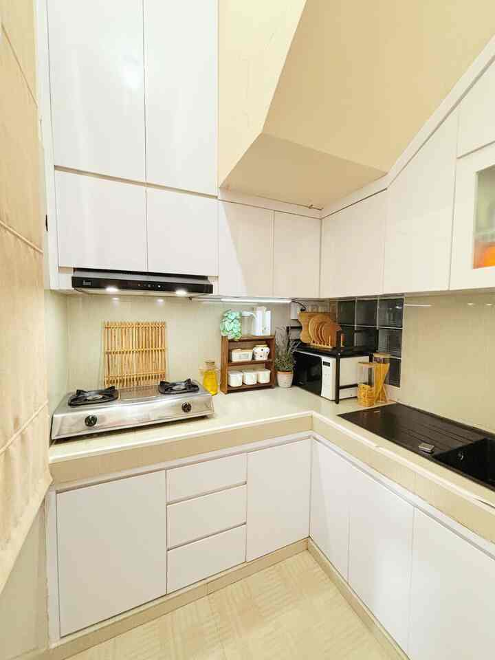 White and beige toned kitchen featuring upper and lower cabinets with a three-tier spice rack, neat and compact space