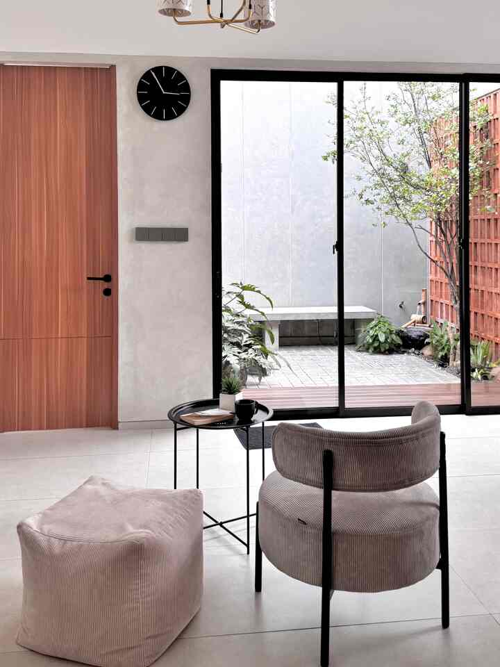 A white and brown toned living room featuring a gray armchair and beige bean bag with a natural, modern feel