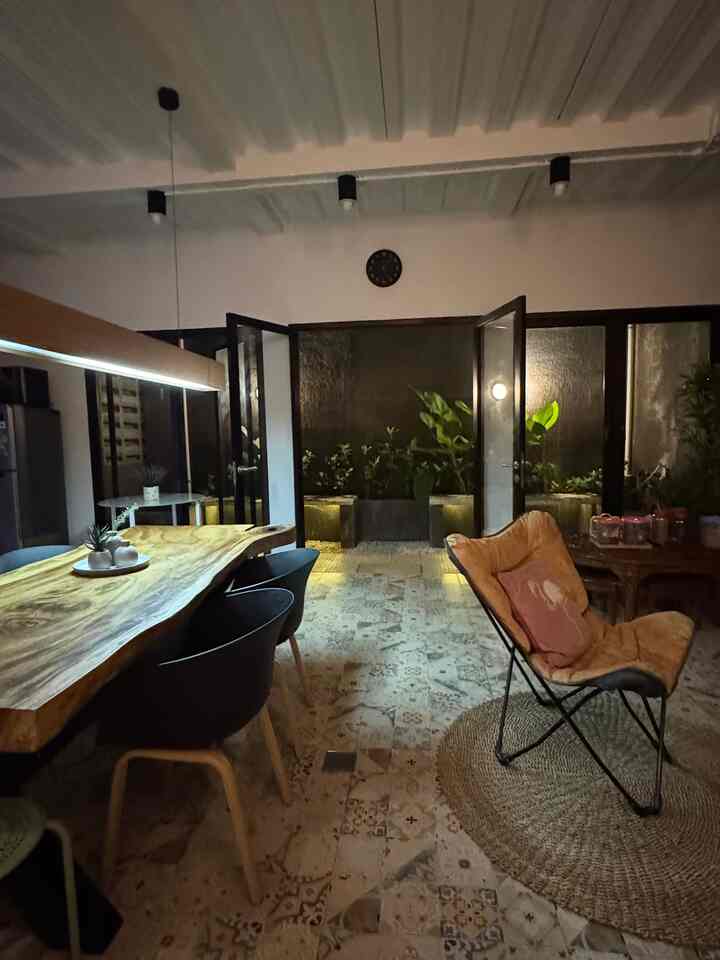 Beige and natural-toned dining room featuring a wooden dining table, armchair, plants, and ambient lighting creating a cozy atmosphere