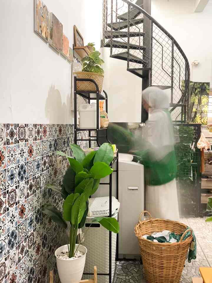 Laundry area ini dirancang dengan cermat di ruang terbatas yang menyatu dengan dapur, menciptakan area cuci yang tetap rapi dan fungsional.

Mesin cuci ditempatkan di sudut dengan rak besi untuk penyimpanan perlengkapan laundry, mengoptimalkan ruang vertikal.

Dekorasi ubin bermotif vintage memberi sentuhan estetik, dipadukan dengan keranjang rotan dan tanaman hias agar terlihat lebih homey. Penyimpanan tertata dengan botol detergen seragam, keranjang pakaian, serta gantungan dinding untuk perlengkapan kecil.

Yang istimewa, hiasan dinding di area ini adalah hasil karya tangan anak kami, menambah kesan personal dan hangat. 
Meski kecil, area ini tetap nyaman, multifungsi, dan hemat ruang—cocok untuk inspirasi laundry minimalis di rumah kecil!

#Wallpaper #LaundryArea #LaundryRoom #LaundryRoomInspo #InspirasiLaundryRoom #laundryRoomMinimalis 
