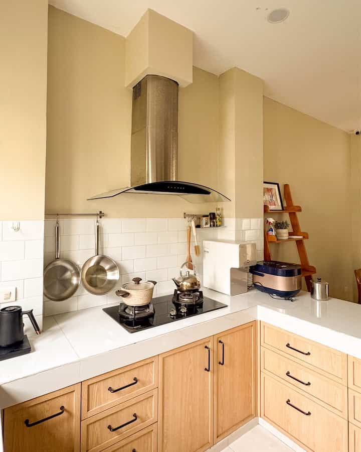 Compact kitchen with warm beige walls and brown cabinets, featuring an organized cooking area