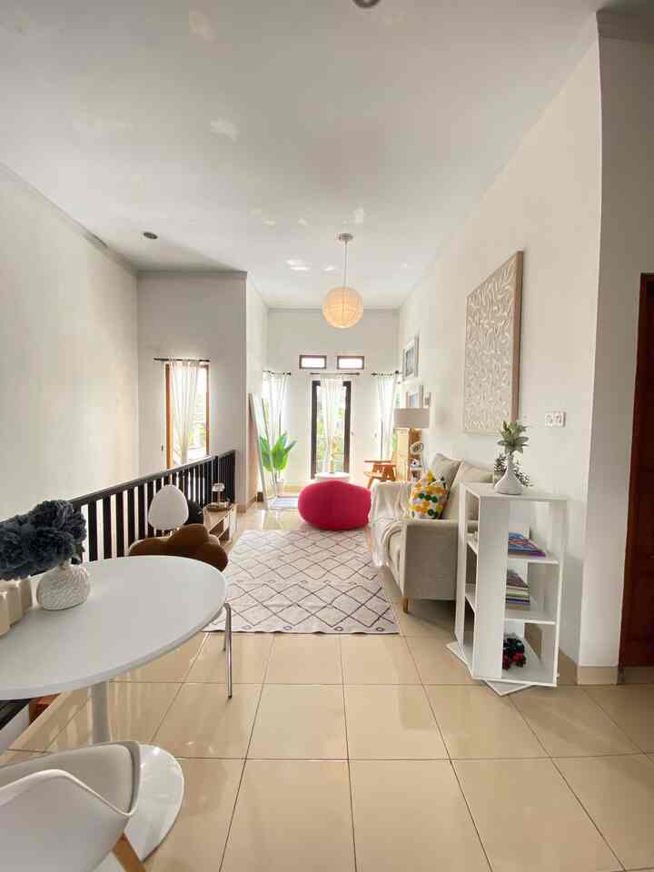 Bright natural beige-toned living room featuring beige sofa, patterned rug, round dining table, and plants into a cozy space