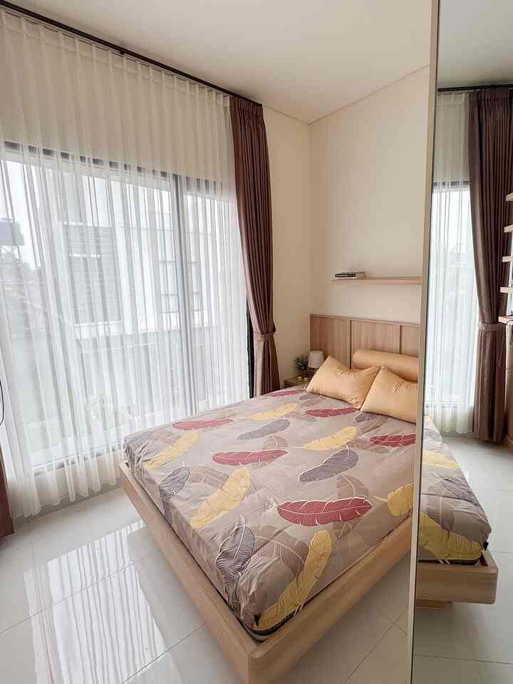 White and brown toned bedroom featuring large windows and a wooden bed, creating a cozy and natural atmosphere