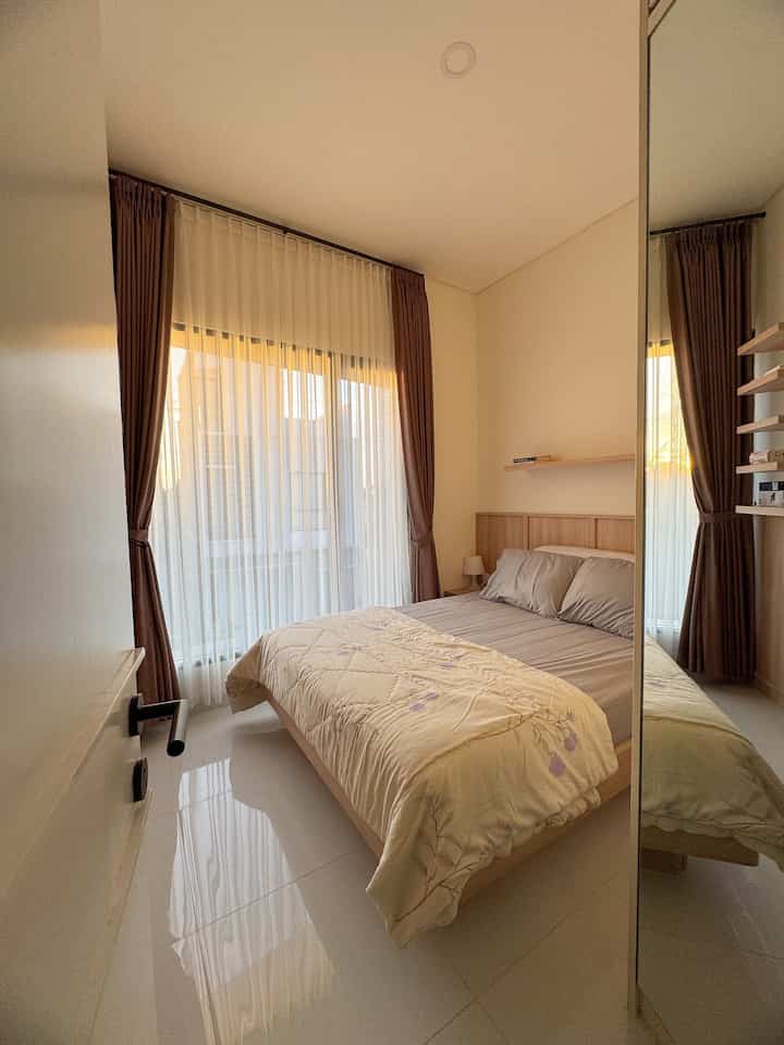 White and brown toned bedroom featuring a natural bed and blackout curtains with a warm atmosphere