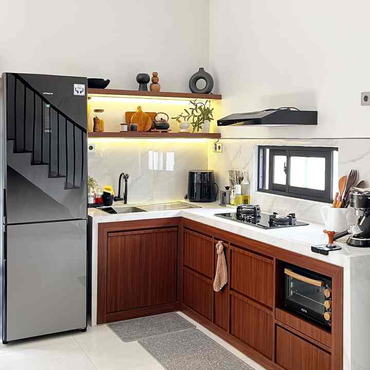 Modern kitchen with white walls and floor, brown wooden cabinets, featuring refrigerator and illuminated shelves