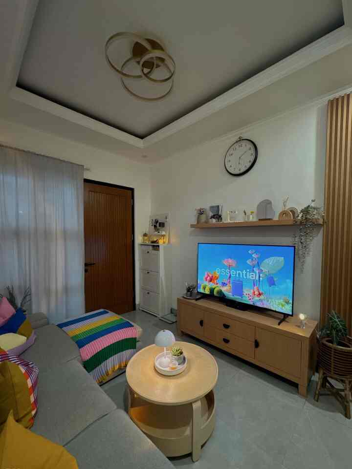 White-walled living room with wood-toned furniture, featuring a sofa and TV stand in a cozy setting