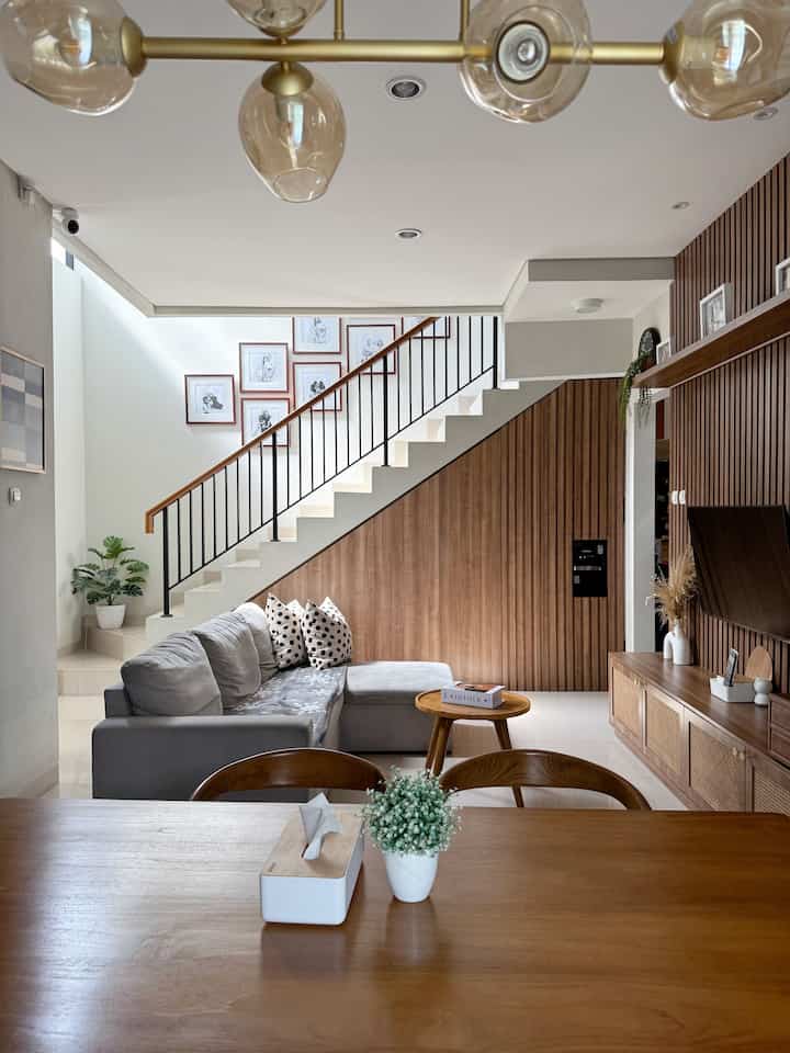 Modern and clean dining and living room with wood tones and natural colors, featuring a gray sectional sofa and a round coffee table