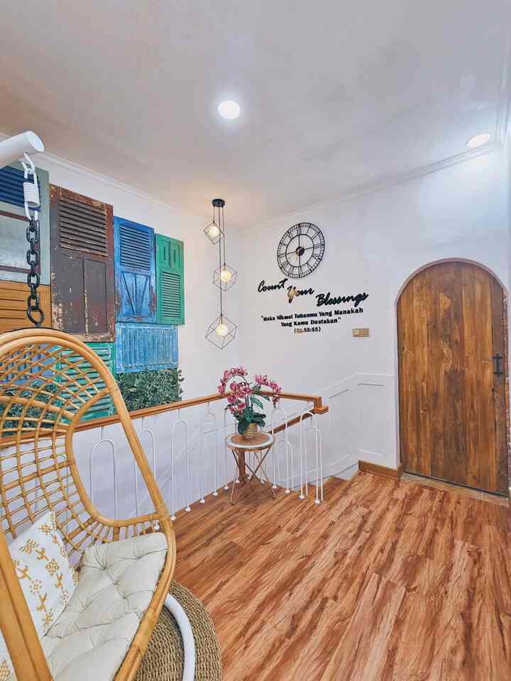 Bright white walls and wood-tone floor define a living room entrance space with wall decor and pendant lighting enhancing ambiance