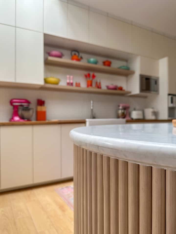 White and wood tone kitchen featuring a kitchen island and colorful kitchen utensils with a modern atmosphere