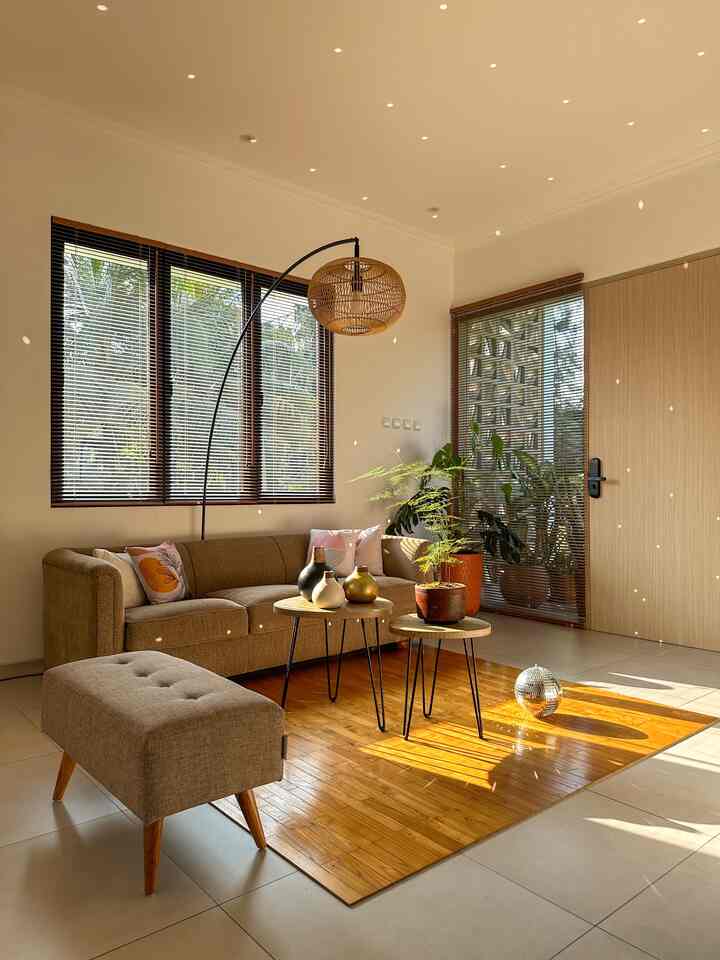Natural color toned living room featuring brown sofa and bench, wooden carpet, and green plants with a warm, cozy atmosphere