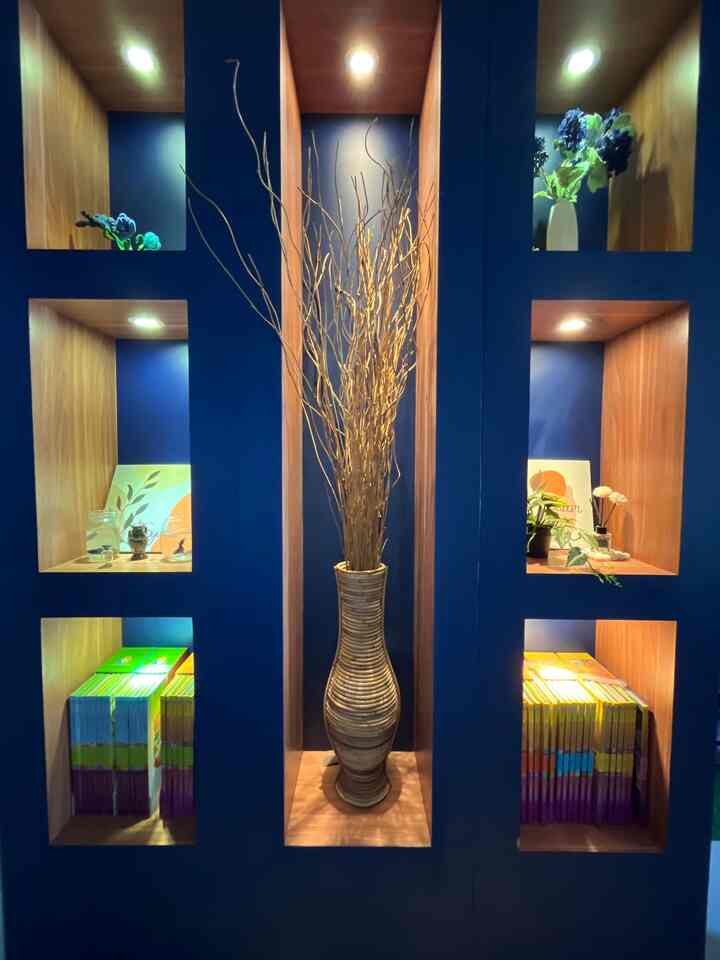 Navy-colored wall with wood-tone recessed niches arranged harmoniously, featuring central vase and plant stand in a stylish interior space
