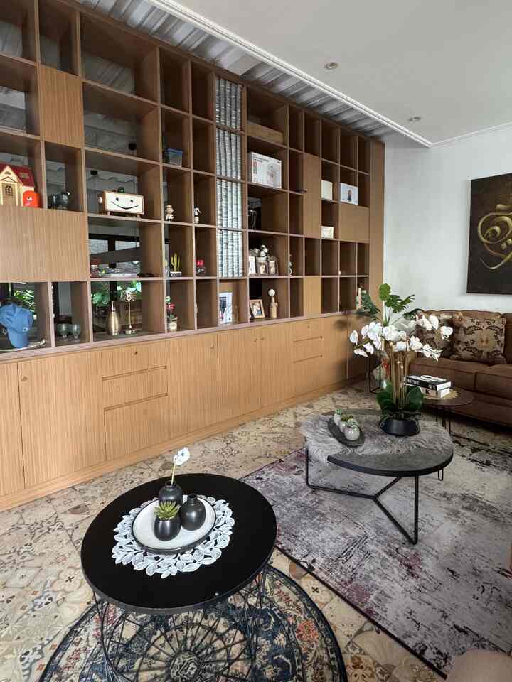 Natural wood tone living room featuring brown sofa, black coffee tables, and various plants creating a cozy atmosphere