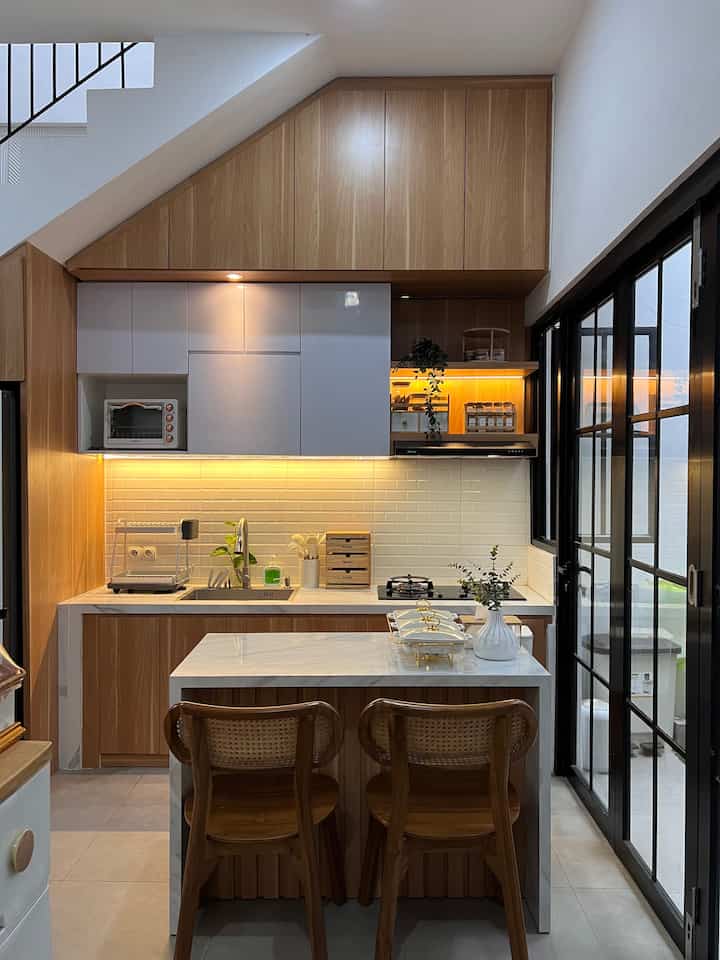 White and wood tone compact kitchen featuring a kitchen island and cabinets with a warm cozy atmosphere