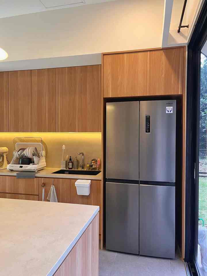 Warm brown-toned kitchen featuring wooden cabinets and a stainless steel refrigerator in a clean, organized interior