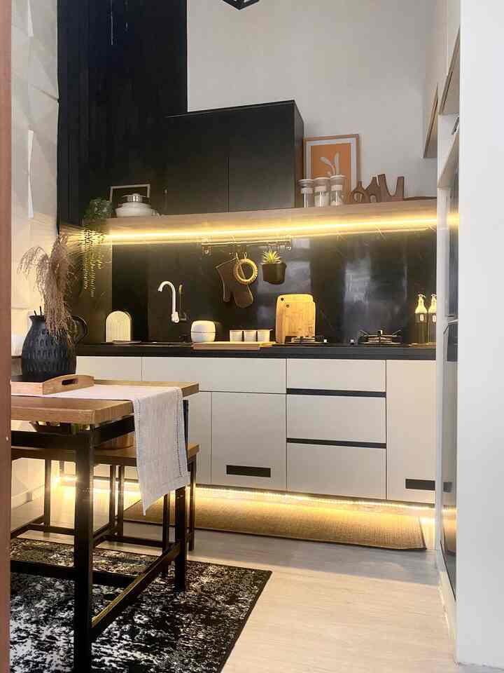 Monotone kitchen with wood accents and under-cabinet lighting creates a neat and cozy atmosphere